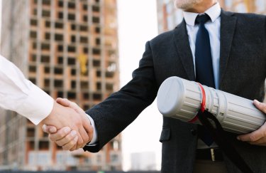 Корупція в цій сфері часто не проявляється у вигляді прямого хабарництва, а маскується під формально законні рішення. / Freepik чоловіки тиснуть руки на тлі будівництва